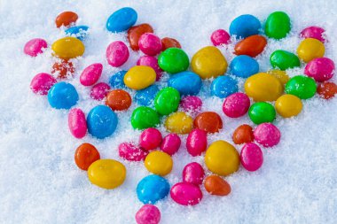 Karda çok renkli kalp şekilli şekerler. Karda şeker. Sevgililer Günü.