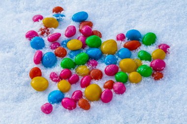 Karda çok renkli kalp şekilli şekerler. Karda şeker. Sevgililer Günü.