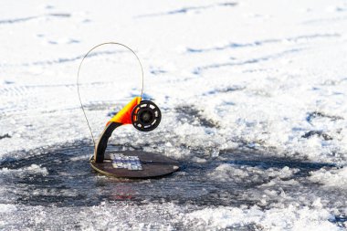 Karla kaplı buz yüzeyinde kış balıkçılığı için olta.