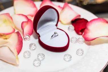 Mumların arka planında gül yapraklarıyla alyans.