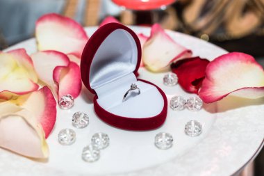 Mumların arka planında gül yapraklarıyla alyans.