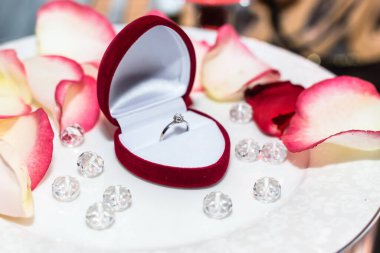 Mumların arka planında gül yapraklarıyla alyans.