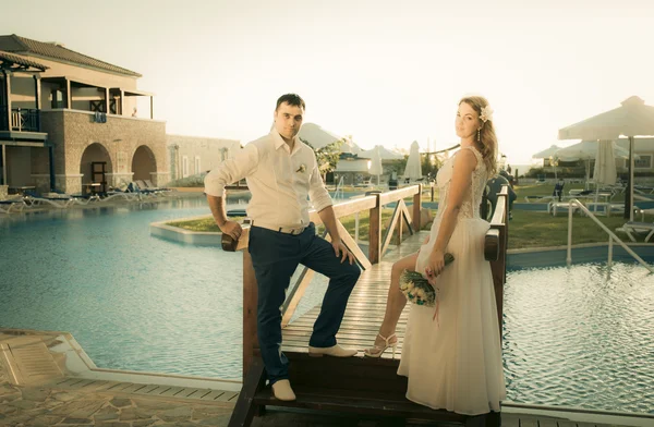 Menyasszony és vőlegény pózol a hídon — Stock Fotó
