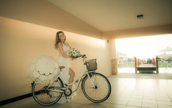 Pengantin dengan karangan bunga dan payung mengendarai sepeda — Stok Foto