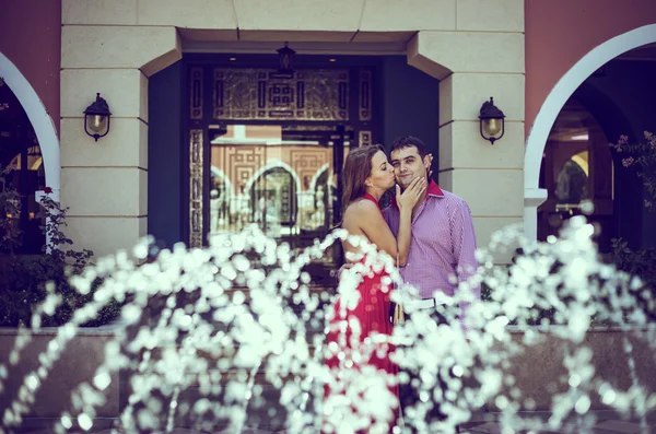 Pareja enamorada posando detrás de la fuente —  Fotos de Stock