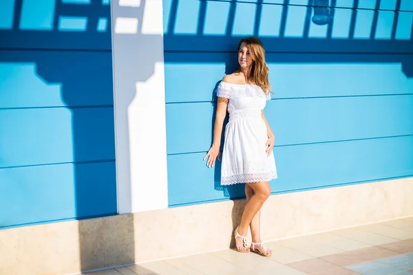 Beautiful young lady posing near blue wall — Stock Photo, Image