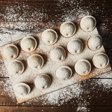 Ahşap arka planda çiğ hamur tatlısı üzerine un serpiştirilmiş.