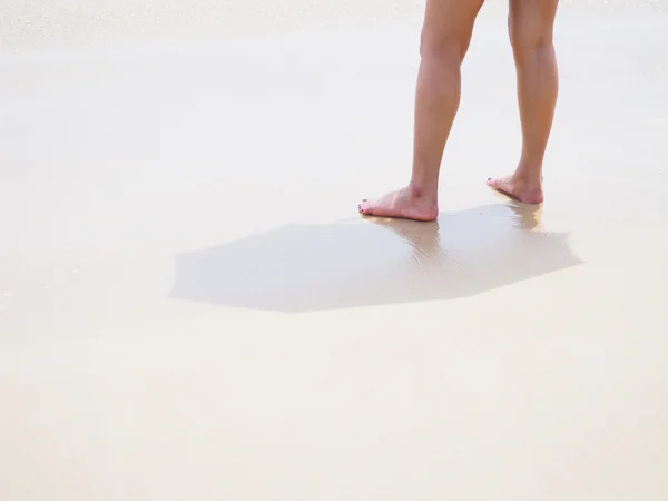 Jambes et pieds de femme debout sur le sable — Photo