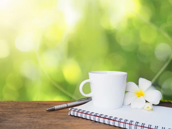 Bílý hrnek kávy, pero a Poznámkový blok na dřevěný stůl — Stock fotografie