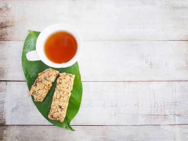Białe filiżanka herbaty i zdrowe muesli na zielony liść — Zdjęcie stockowe