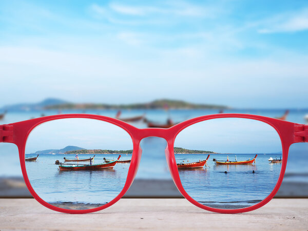 Summer beach focused in red glasses lenses