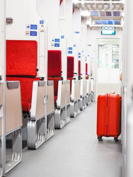 Red luggage bag put on walkway beside passenger in second class sleeper cabin of Thai new express train. Holiday vacation concept.