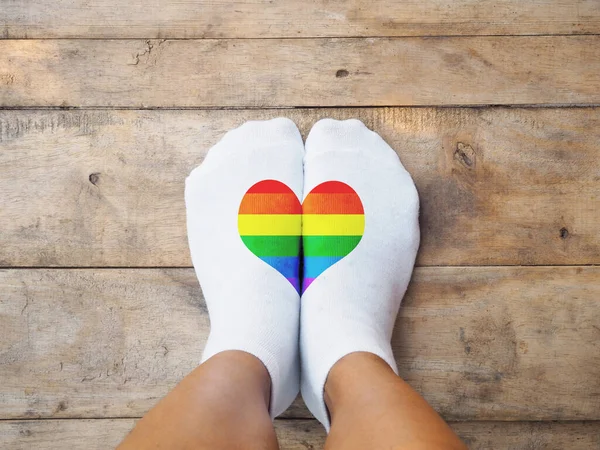 木製の床の背景に虹色のハート型の白い靴下を着てセルフィー足 Lbgt愛のコンセプト — ストック写真