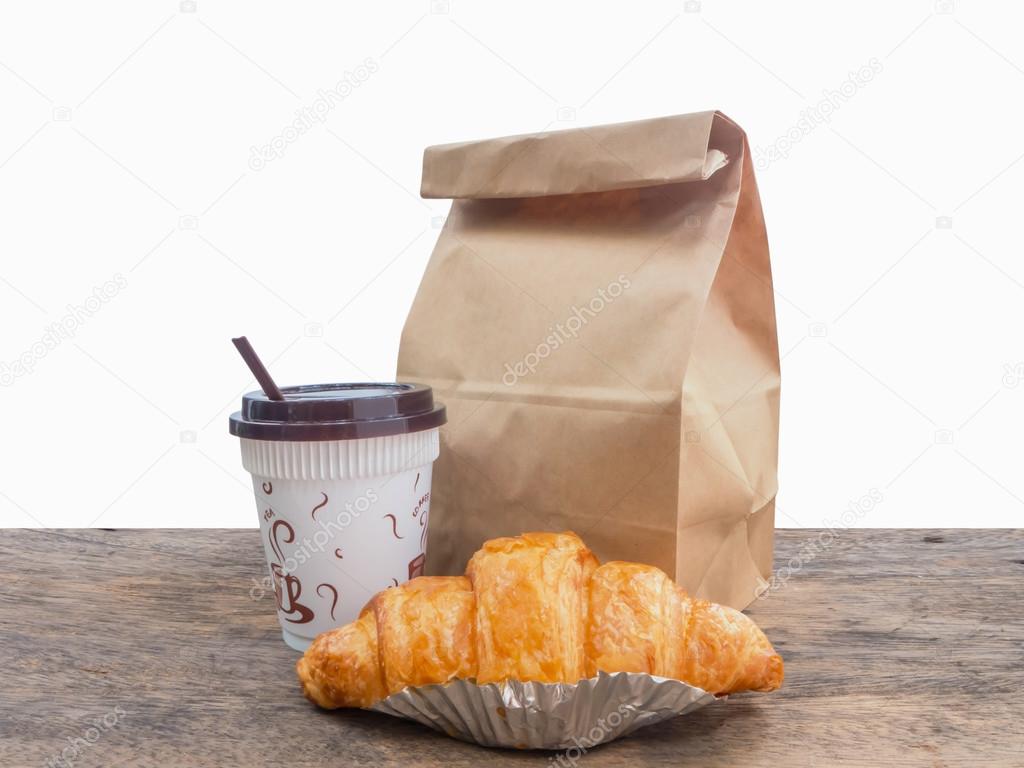 coffee and croissant with paper bag on table