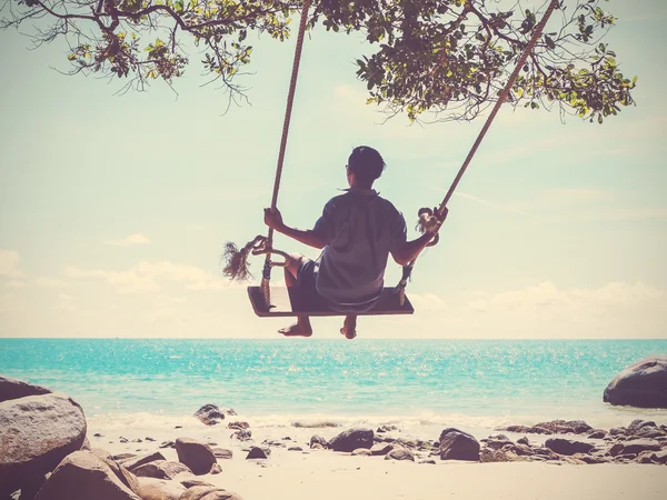Jonge man swingen op het strand — Stockfoto
