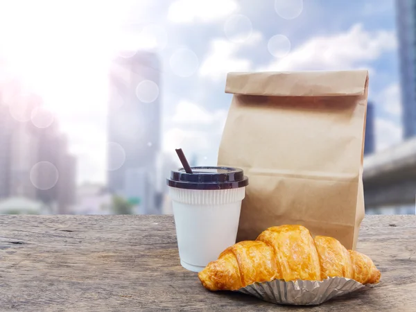 Kávé és croissant reggelire papír zsák — Stock Fotó