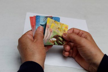 Kosta Rika banknotlarını farklı değerlerde sayan yaşlı bir kadının ellerine yaklaşmak