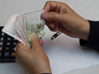 Tek kişilik banknotları sayan yaşlı bir kadının elleri