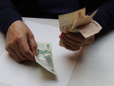 Uruguay banknotlarını sayan yaşlı bir kadının elleri.