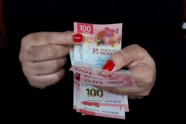 Meksika banknotlarından 100 peso sayan bir kadının elleri