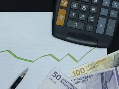 Arkaplanda Danimarka banknotları, kalem ve hesap makinesi ve yükselen yeşil çizgi