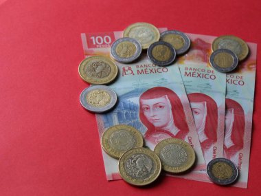 Kırmızı arka planda 100 pesoluk Meksika paraları ve banknotları