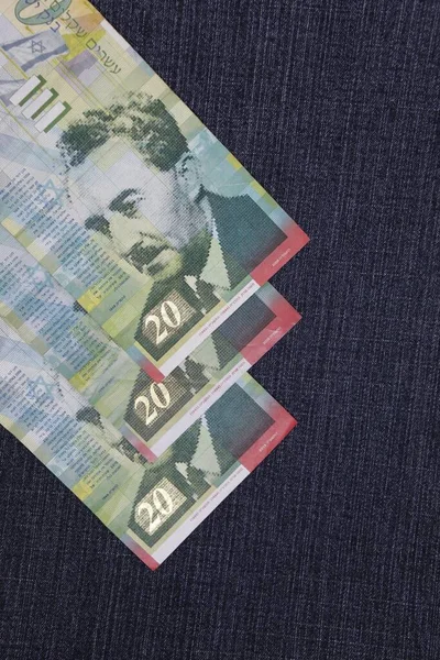 israeli banknotes of twenty shekels between blue denim fabric