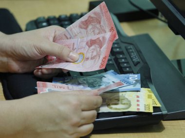 Bilgisayar klavyesinde Kosta Rika parası tutan bir kadının elleri