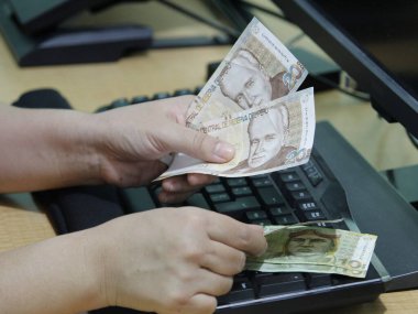 Peru parasını bilgisayar klavyesinde tutan bir kadının elleri