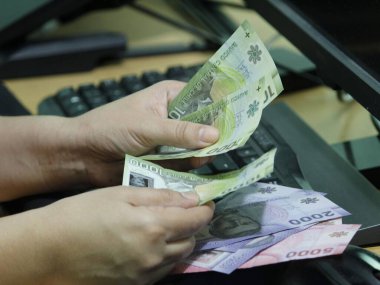 Şili parasını bilgisayar klavyesinde tutan bir kadının elleri