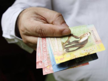 Kosta Rika banknotlarını tutan bir adamın eli