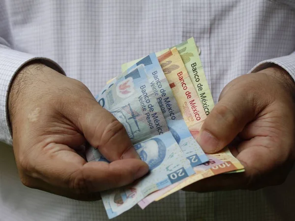 Meksika banknotları tutan bir adamın elleri.
