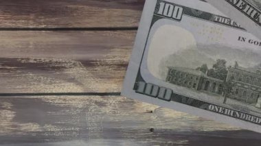 Tahta arka planda 100 dolarlık yığınla Amerikan banknotlarının animasyonu