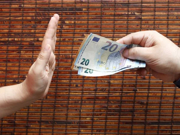 hand of a person giving european money and hand of another person rejecting