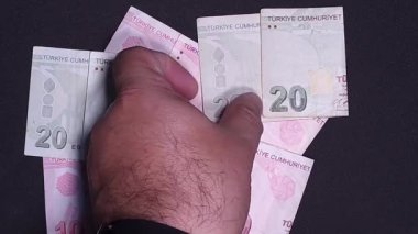 Hand placing folded Turkish banknotes on the table, top view
