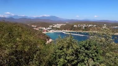 Huatulco gemi terminalinin yaz mevsiminde dağlarla mavi deniz arasındaki panoramik görüntüsü.