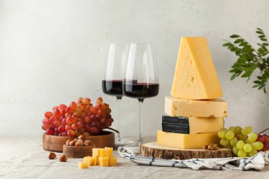 Üzümlü çeşitli peynirler ve keten bir masa örtüsünün üzerinde bir bardak kırmızı şarap. Boşluğu kopyala.