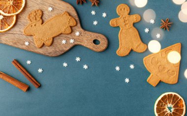 Noel arkaplanda zencefilli kurabiyeler ve baharatlar, mavi arka planda Noel ışıkları. Boşluğu kopyala.