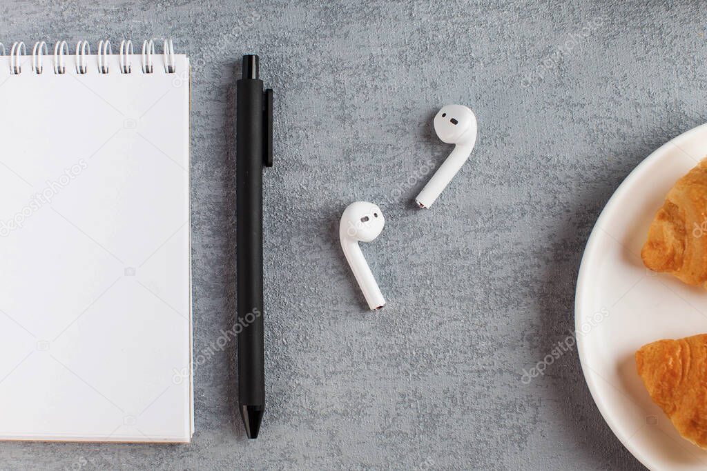 White Notepad, wireless headphones. The concept of online training, work from home, home office. Copy space.