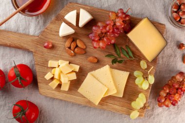 Peynir tabağı. Tahta bir tahtanın üzerinde üzümlü peynirler, tatlım, keten bir masa örtüsünün üzerinde fındıklar. Yüksek kalite fotoğraf