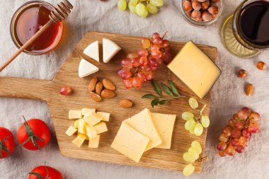 Peynir tabağı. Tahta bir tahtanın üzerinde üzümlü peynirler, tatlım, keten bir masa örtüsünün üzerinde fındıklar. Yüksek kalite fotoğraf
