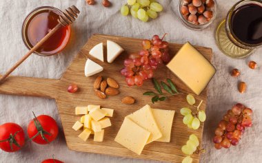 Peynir tabağı. Tahta bir tahtanın üzerinde üzümlü peynirler, tatlım, keten bir masa örtüsünün üzerinde fındıklar. Yüksek kalite fotoğraf