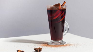 Mulled wine in a glass with a stick of cinnamon and spices. Food photo with hard light. High quality photo clipart
