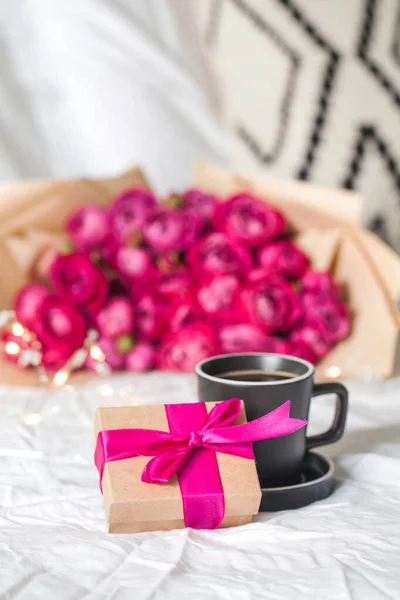 Tasse à café et cadeau au lit sur fond de bouquet de fleurs. Concept de Saint-Valentin, le 8 mars. — Photo