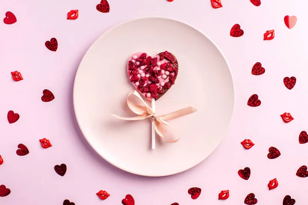 Chocolate heart on a pink plate on a pink background. The concept of a romantic dinner, Valentines Day. — Stock Photo, Image