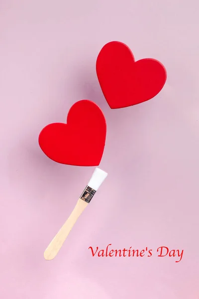 Concept d'art des cartes de voeux de la Saint-Valentin. Deux cœurs rouges sur un pompon sur un fond rose. — Photo