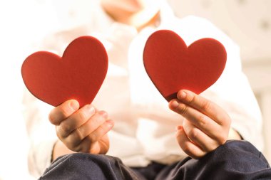 Çocuğun elinde iki kırmızı kalp var. Aşk konsepti, Sevgililer Günü.