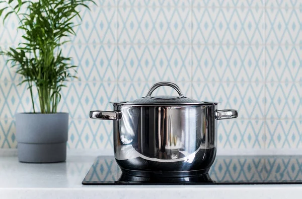 A metal pot on an electric induction cooker in a modern kitchen. Copy space. — Stock Photo, Image