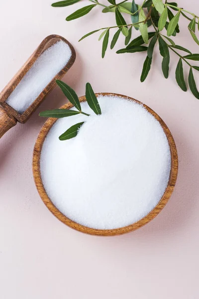 Natural sweetener in a wooden bowl on a pink background. Sugar substitute. Erythritol.