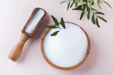 Pembe arka planda tahta bir kasede doğal tatlandırıcı. Şekerin yerine. Eritritol!. 